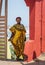 Africa Woman wearing yellow suit stands at a gate