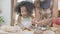 African America family with mother wearing apron rolling thresh flour for cooking with daughter together.