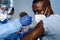 African americam man looking at coronavirus covid-19 syring when medical staff injecting vaccine to arm muscle to build