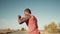 African-American athlete black man practice series of boxing punches outdoor background sky, side view. Fighter training