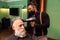 African-American barber combs and blow-drys a bearded man`s hair