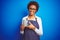 African american barista woman wearing bartender uniform holding cup over blue background with a happy face standing and smiling