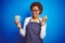African american barista woman wearing bartender uniform holding cup over blue background screaming proud and celebrating victory
