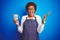 African american barista woman wearing bartender uniform holding cup over blue background very happy and excited, winner