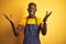 African american bartender man wearing apron standing over isolated yellow background celebrating crazy and amazed for success