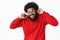 African american bearded guy in red hoodie grimacing, close eyes intense and clenching teeth as preparing to loud noise