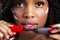 African american black woman with curly black hair and flowers smiles while wearing pink lipstick.