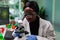African american botanist looking at leaf sample using medical microscope