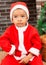 African American boy dressed costume Santa Claus by fireplace.