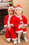 African American boy and girl dressed costume Santa Claus by fireplace.