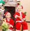 African American boy and girl dressed costume Santa Claus by fireplace. Christmas