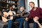 African american boy playing acustic guitar while his friends listening and singing at home