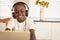 African American boy playing game on digital tablet at dining table in kitchen