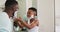 African american boy putting shaving cream on his father face and laughing together