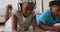 African american brother and sister using electronic devices lying on the floor at home