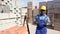 African-american builder standing beside brick stacks in outdoor construction material warehouse.