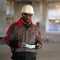 African american builder stands at construction site and holds medical mask