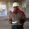 African american builder stands at construction site and holds medical mask