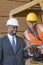 African American businessman and female industrial worker looking at tablet PC