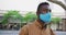 African american businessman wearing face mask sitting in park