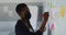 African american businesswoman wearing face mask, thinking and making notes on whiteboard