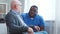 African-American caregiver and old disabled man in a wheelchair. Professional nurse and handicapped patient in a nursing