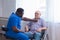 African-American caregiver and old disabled man in a wheelchair. Professional nurse and handicapped patient in a nursing