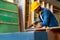 African American carpenter man use sawing wood to work with timber on table during work in factory workplace area