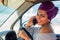 African american caucasian woman in a purple turban head posing with her new car showing the key outdoors, outside in