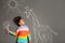 African-American child playing with chalk drawing of giraffe and flowers on grey