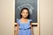 African-American child standing at blackboard with chalk drawn academic cap. Education