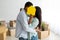 African american couple kissing behind paper house model in hand, moving to new home, celebrating relocation