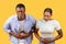 African american couple with stomach pain, uncomfortable expressions, yellow background