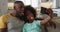 African american daughter and her father making faces taking selfie together on couch