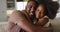 African american daughter and her father smiling and embracing on couch