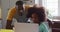 African american daughter and her father using laptop together at kitchen table