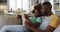 African american daughter and her father using tablet together sitting on couch