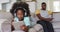 African american daughter wearing headphones using tablet while her father watching tv