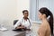 An African-American doctor holds a form in her hand and records the patient's testimony. They are located in a