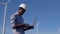 An African American electrical engineer is standing against the backdrop of a windmill at an air power plant with a