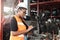 African American engineer worker woman wearing helmet and checking product stock at auto spare parts store shop warehouse with