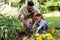 African american father assisting son in digging dirt with tools on grassy field in backyard