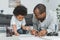 african american father drawing with son on floor