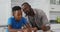 African american father sitting at kitchen table helping son with school work
