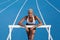 An African American female athlete is training on the Olympic track, leaning against the hurdles, with blue lanes in the