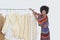 African American female designer with sewing patterns on clothes rack over gray background