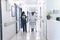 African american female doctor walking with senior female patient with crutches in hospital corridor