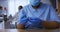 African american female doctor wearing face mask inspecting vial of covid vaccine in hospital