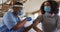 African american female doctor wearing face mask vaccinating african american patient