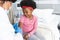 African american female doctor wearing face mask vaccinating girl patient at hospital